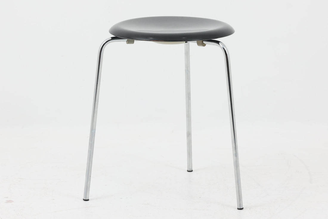 1954年、デンマークのデザイナー、Arne Jacobsen（アルネ・ヤコブセン）によって発表された3本脚のスツール、「DOT（ドット）」。このスツールは、ヤコブセンが手がけた「ルードブレ市庁舎」のロビーで待合席として使用されていました。3本脚のモデルはビンテージ品のみで入手可能です。オフィスや自宅での日常的な使用はもちろん、予備の椅子としても便利なこのスツールは、シンプルなデザインが魅力です。座面の中央がわずかにくぼんでおり、座った際にフィット感を生み出します。シンプルながらもヤコブセンのこだわりが感じられ、また、単なるスツールとしてだけでなく、ソファの横に置いて本や小物を置くサイドテーブルとしても活用できます。