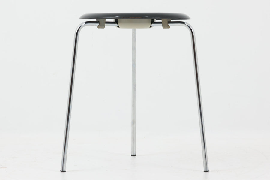 1954年、デンマークのデザイナー、Arne Jacobsen（アルネ・ヤコブセン）によって発表された3本脚のスツール、「DOT（ドット）」。このスツールは、ヤコブセンが手がけた「ルードブレ市庁舎」のロビーで待合席として使用されていました。3本脚のモデルはビンテージ品のみで入手可能です。オフィスや自宅での日常的な使用はもちろん、予備の椅子としても便利なこのスツールは、シンプルなデザインが魅力です。座面の中央がわずかにくぼんでおり、座った際にフィット感を生み出します。シンプルながらもヤコブセンのこだわりが感じられ、また、単なるスツールとしてだけでなく、ソファの横に置いて本や小物を置くサイドテーブルとしても活用できます。