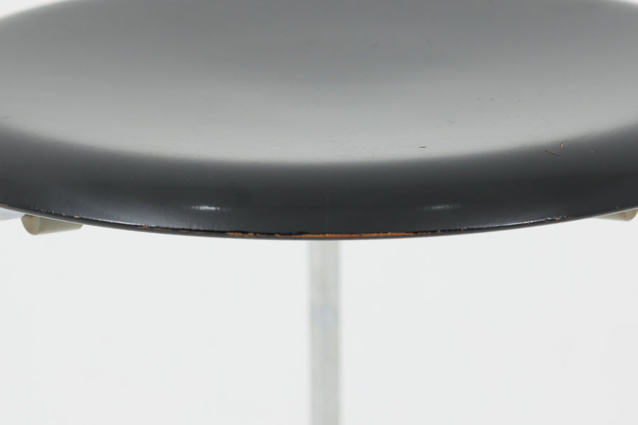 1954年、デンマークのデザイナー、Arne Jacobsen（アルネ・ヤコブセン）によって発表された3本脚のスツール、「DOT（ドット）」。このスツールは、ヤコブセンが手がけた「ルードブレ市庁舎」のロビーで待合席として使用されていました。3本脚のモデルはビンテージ品のみで入手可能です。オフィスや自宅での日常的な使用はもちろん、予備の椅子としても便利なこのスツールは、シンプルなデザインが魅力です。座面の中央がわずかにくぼんでおり、座った際にフィット感を生み出します。シンプルながらもヤコブセンのこだわりが感じられ、また、単なるスツールとしてだけでなく、ソファの横に置いて本や小物を置くサイドテーブルとしても活用できます。