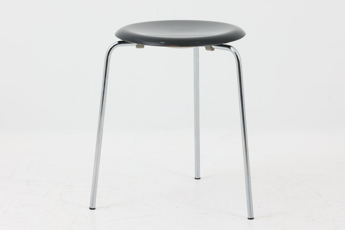 1954年、デンマークのデザイナー、Arne Jacobsen（アルネ・ヤコブセン）によって発表された3本脚のスツール、「DOT（ドット）」。このスツールは、ヤコブセンが手がけた「ルードブレ市庁舎」のロビーで待合席として使用されていました。3本脚のモデルはビンテージ品のみで入手可能です。オフィスや自宅での日常的な使用はもちろん、予備の椅子としても便利なこのスツールは、シンプルなデザインが魅力です。座面の中央がわずかにくぼんでおり、座った際にフィット感を生み出します。シンプルながらもヤコブセンのこだわりが感じられ、また、単なるスツールとしてだけでなく、ソファの横に置いて本や小物を置くサイドテーブルとしても活用できます。