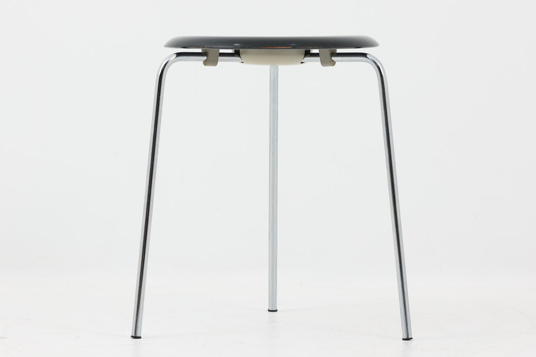 1954年、デンマークのデザイナー、Arne Jacobsen（アルネ・ヤコブセン）によって発表された3本脚のスツール、「DOT（ドット）」。このスツールは、ヤコブセンが手がけた「ルードブレ市庁舎」のロビーで待合席として使用されていました。3本脚のモデルはビンテージ品のみで入手可能です。オフィスや自宅での日常的な使用はもちろん、予備の椅子としても便利なこのスツールは、シンプルなデザインが魅力です。座面の中央がわずかにくぼんでおり、座った際にフィット感を生み出します。シンプルながらもヤコブセンのこだわりが感じられ、また、単なるスツールとしてだけでなく、ソファの横に置いて本や小物を置くサイドテーブルとしても活用できます。